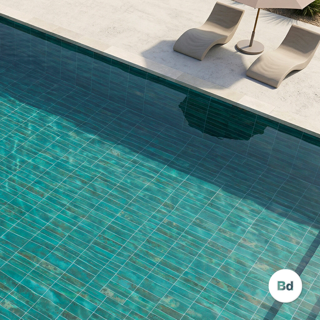 Top-down view of a turquoise tiled pool with two beige lounge chairs and a patio umbrella on the deck.