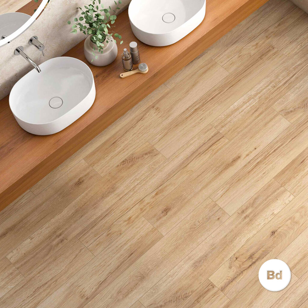 Double white oval vessel sinks on a wooden vanity with a small plant and grooming items, against a light wood floor.