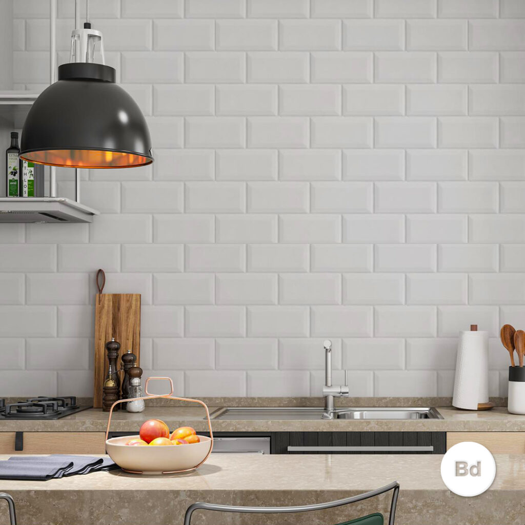 Modern kitchen with white subway tile backsplash, a large black pendant light, and a bowl of fruit on a beige countertop.